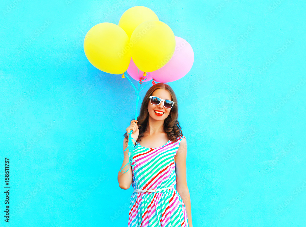 Summertime! happy smiling woman holds in hand an air colorful balloons is having fun on a blue background Summertime! happy smiling woman holds in hand an air colorful balloons is having fun on a blue background