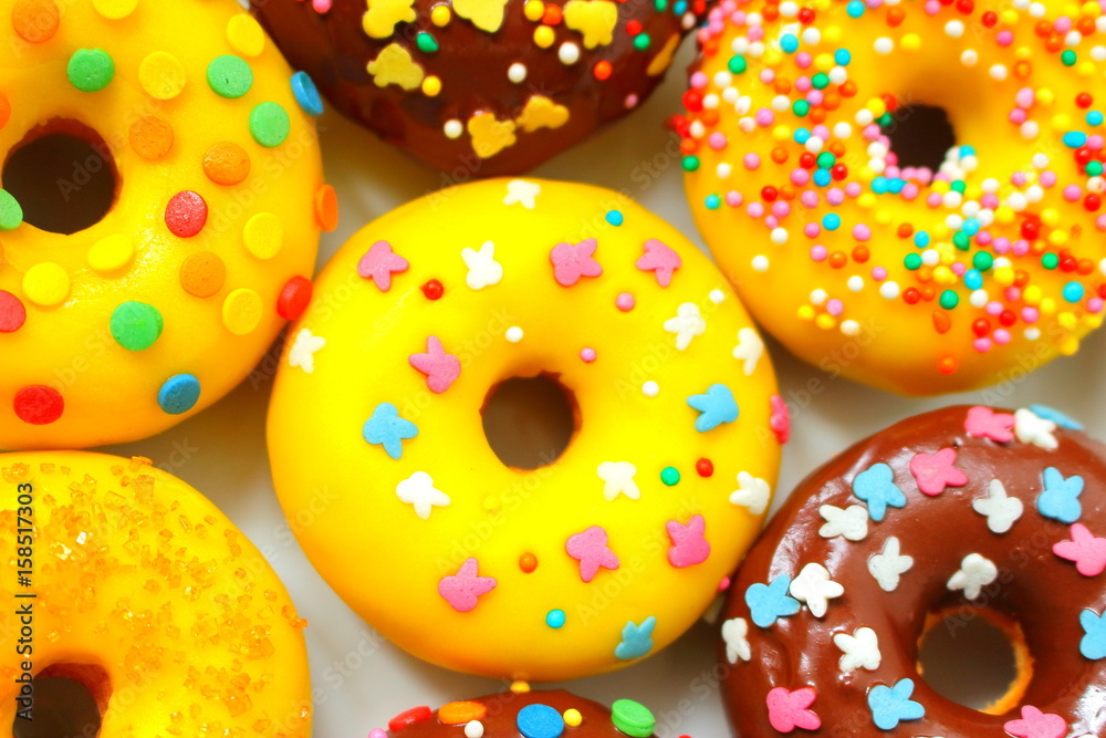 Donuts on a white background. Rainbow dots decoration. Brown sugar. Lemon, melon, pineapple, mango, banana flavour