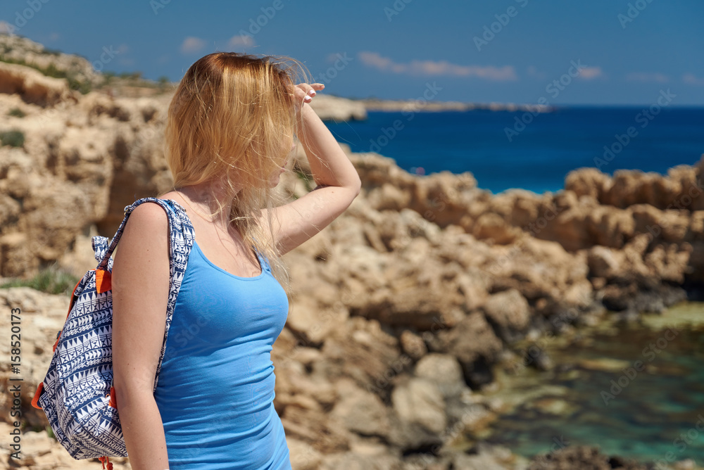 Beautiful young woman is looking to the sea being on the picturesque cliffy coast. Cape Greko. Cyprus. Beautiful young woman is looking to the sea being on the picturesque cliffy coast. Cape Greko. Cyprus.