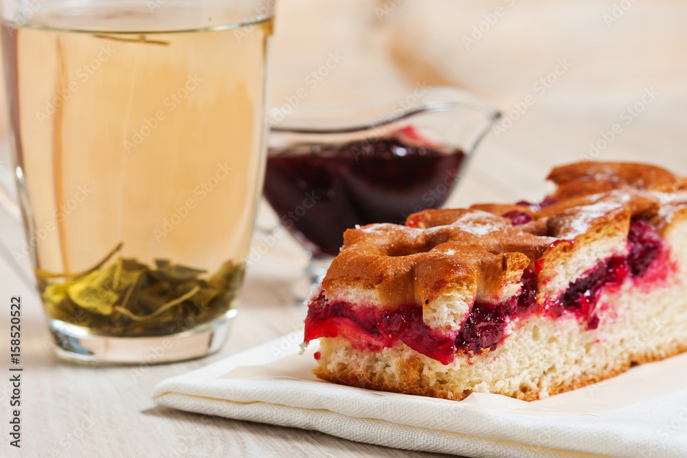 Pie with cherries, cherry jam, tea and white napkin on the table. Dessert, sweet, tea. Green tea. Early morning, breakfast. The background
