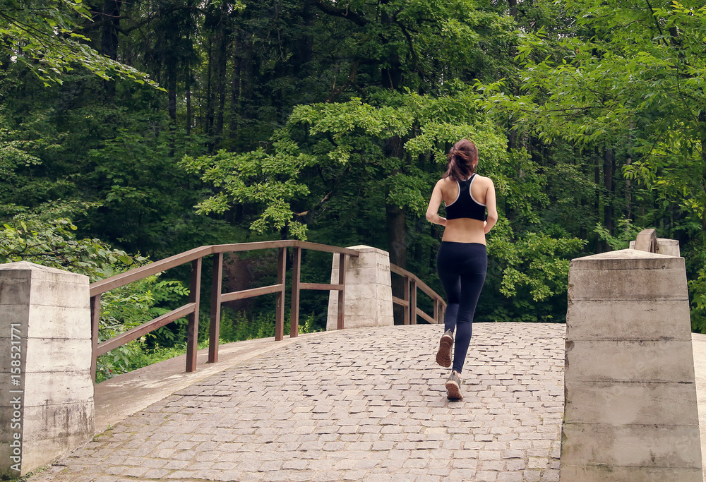 Young woman runs on a stone bridge in the forest. Instagram Young woman runs on a stone bridge in the forest. Instagram