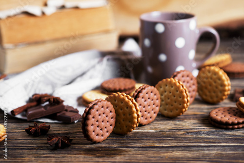Sweets and desserts, chocolate and milk biscuits sandwich, cracker with cinnamon and tea on a dark wooden rustic background 