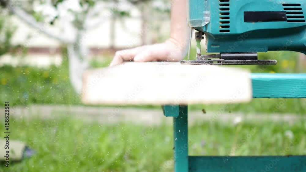 Man saws a board using a jig saw Man saws a board using a jig saw