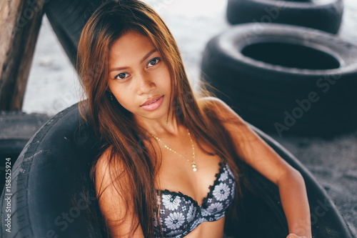 Young beautiful girl sitting in the truck tire on the beach