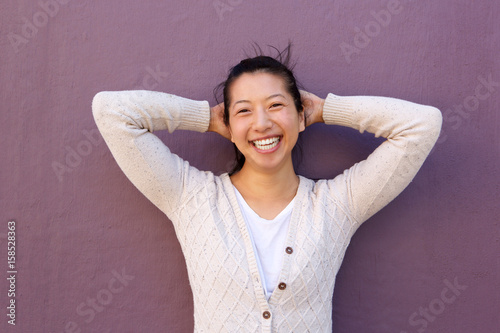 Obraz na plátně Close up joyful asian woman standing with hands behind head