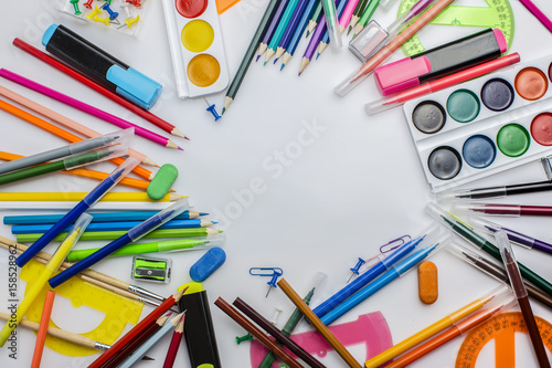 Multicolored stationery on a white table in a light mess. Copy space. Texture.