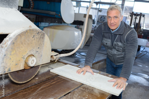 Portrait of senior worker using bench saw