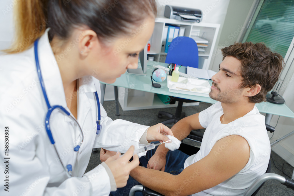 Doctor preparing injection for man in wheelchair Doctor preparing injection for man in wheelchair