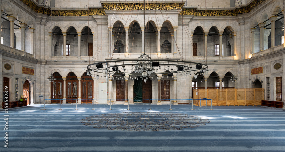Naklejka premium Interior of Nuruosmaniye Mosque, an Ottoman Baroque style mosque completed in 1755, with arcades, wooden doors, windows, and blue carpet, located in Shemberlitash, Fatih, Istanbul, Turkey