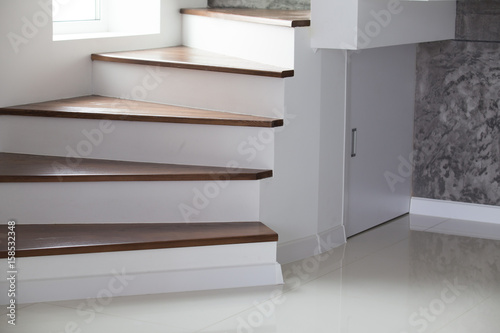 White and wooden stairs on black or grey stone wall in interior