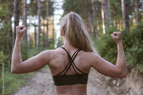 Back view of muscular sporty woman in forest