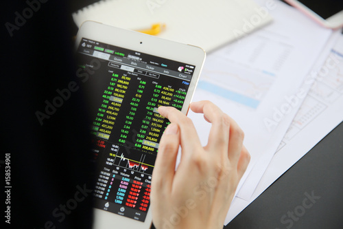 Woman hand Trading online on tablet with business paper and coffee