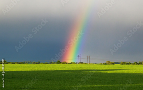 beautiful landscape with green meadow and a bright rainbow in the sky