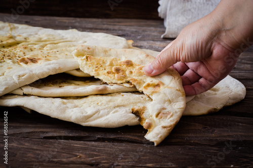 Homemade freshly baked Flatbread - Middle Eastern multi seeded flatbread with seasame seeds on woode3n background. Toned image