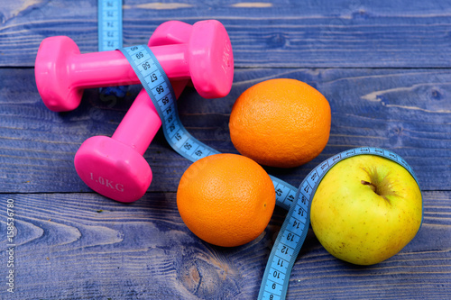 sport training concept, dumbbells weight with measuring tape, orange, apple