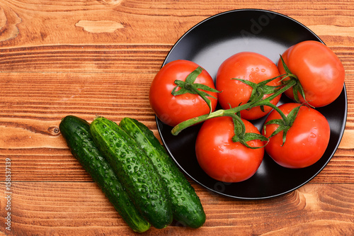 cherry tomato with cucumbers on black plate on brown vintage