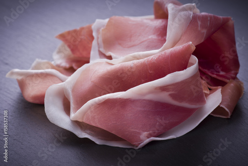 Raw ham leg sliced on the slate