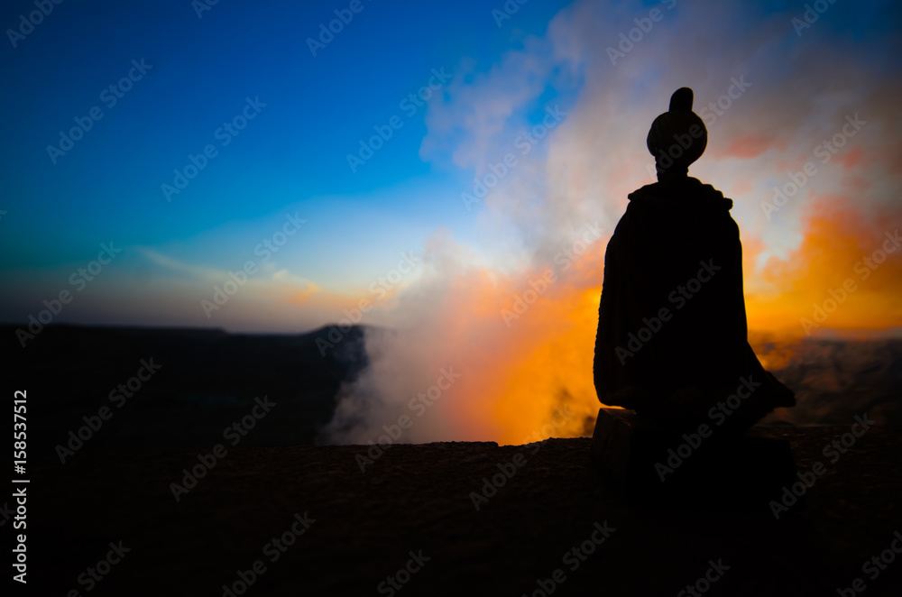 Silhouette of Arab man stands alone in the desert and watching the sunset with clouds of fog. Eastern Fairytale Silhouette of Arab man stands alone in the desert and watching the sunset with clouds of fog. Eastern Fairytale