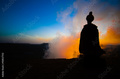 Silhouette of Arab man stands alone in the desert and watching the sunset with clouds of fog. Eastern Fairytale