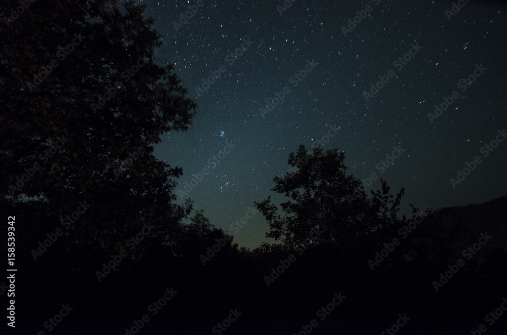 Mountain Road through the forest on a full moon night. Scenic night landscape of dark blue sky with moon. Azerbaijan. Long shutter photo