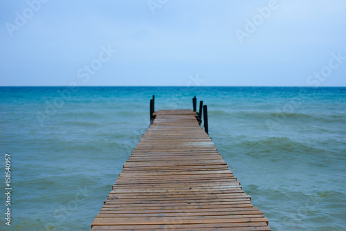 Wooden brown pier in waves sea or ocean in sunny day with horizon background and free space for advertising diving product. Perfect place for a fishing in relax time. Water energy on fresh air.