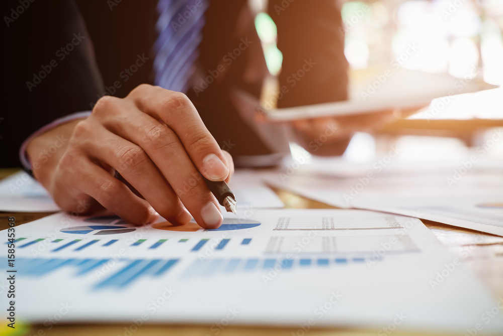 Business man pointing to financial graph in the conference.Business meeting time working with new startup project.Notebook and laptop on wood table.presentation concept, Accounting analyze plans.