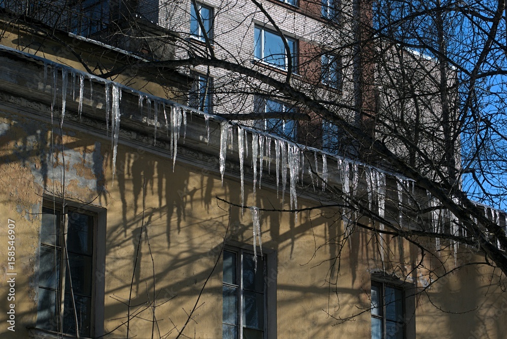 Many hanging icicles from the metal roof of the old house.