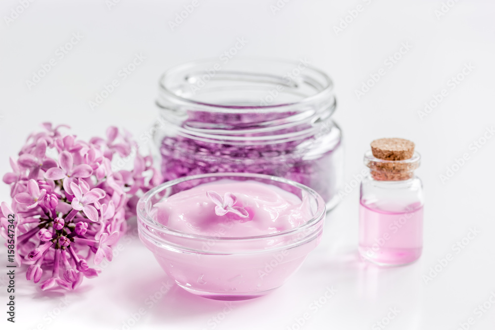 lilac cosmetics with flowers and spa set on white table background lilac cosmetics with flowers and spa set on white table background