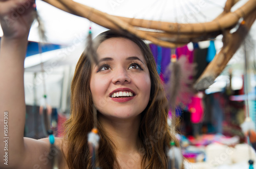 Beautiful smiling woman looking a blurred cardreams in the andean traditional clothing and handicrafts, market background