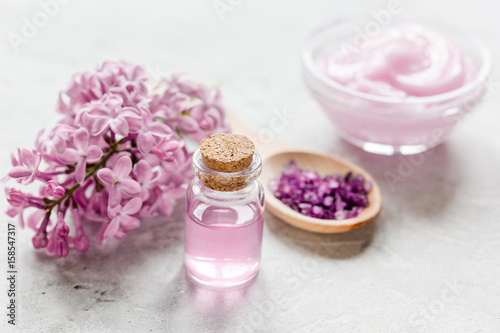 spa cosmetic set with lilac flowers stone desk background