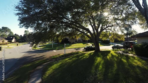 Aerial view of the front yard with a street sign and sunlight coming through tree branches