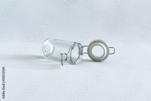 An empty glass jar with open clip lid on a white background