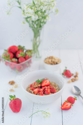 Summer healthy breakfast. Oatmeal with strawberries, walnuts, cashew nut, flax seed and mint on a white background on a wooden table. Cleansing the body. Products for weight loss. Wellness.
