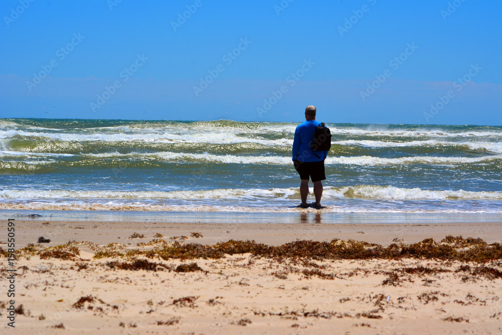 Looking to sea/Man standing in the shallow tide, looking out to sea