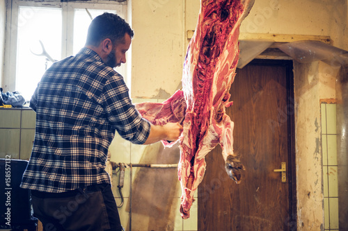 Bearded butcher cuts up the carcass of wild pig.