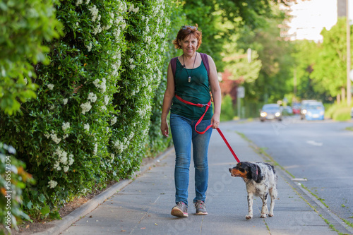 mature woman with Brittany dog on a sidewalk
