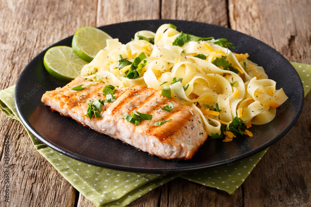 Pasta fettuccine with cheese and butter and grilled salmon with herbs close-up. horizontal Pasta fettuccine with cheese and butter and grilled salmon with herbs close-up. horizontal