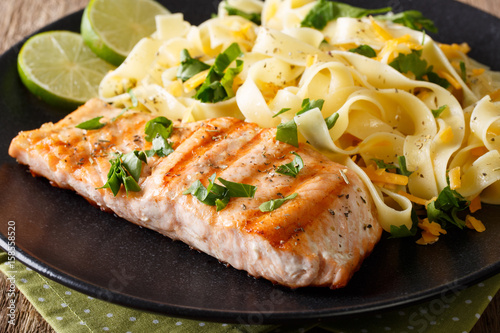grilled salmon garnished with fettuccini pasta with cheese, herbs closeup. horizontal