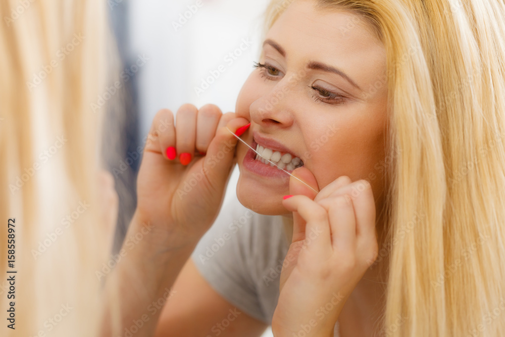 Woman cleaning her teeth using dental floss
