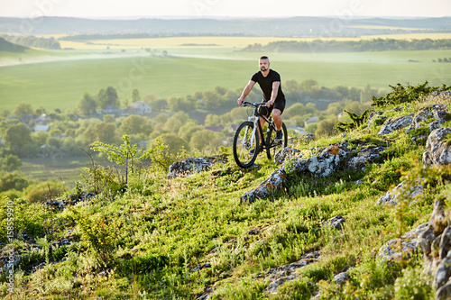 Young cyclist riding the bike on the rocky trail against beautiful landscape.
