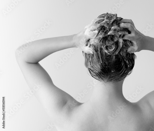 Woman shampooing her hair from the back in black and white