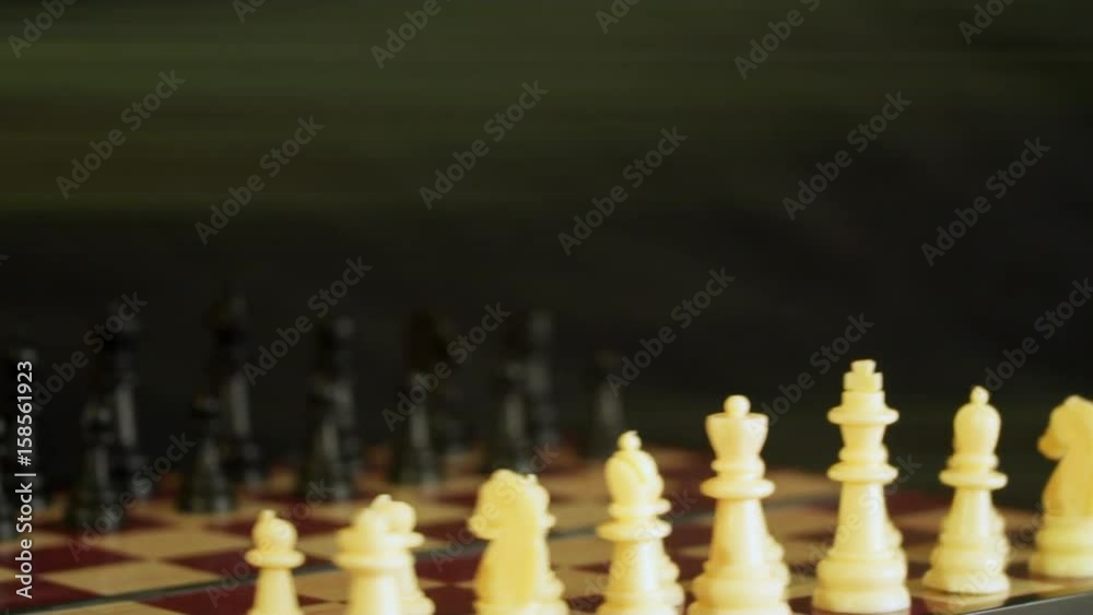 On the chessboard are arranged figures. The board rotates. In the background light rays On the chessboard are arranged figures. The board rotates. In the background light rays