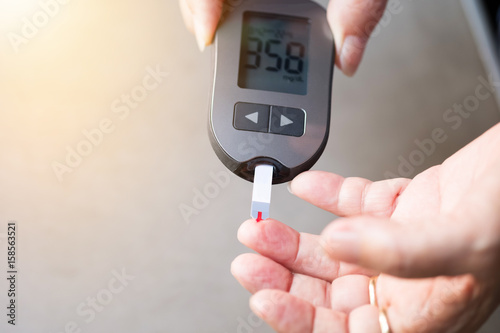 old women checks the amount of sugar in the blood. High blood sugar lever.