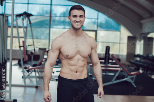Sexy muscular man in gym working out. Strong male naked torso.