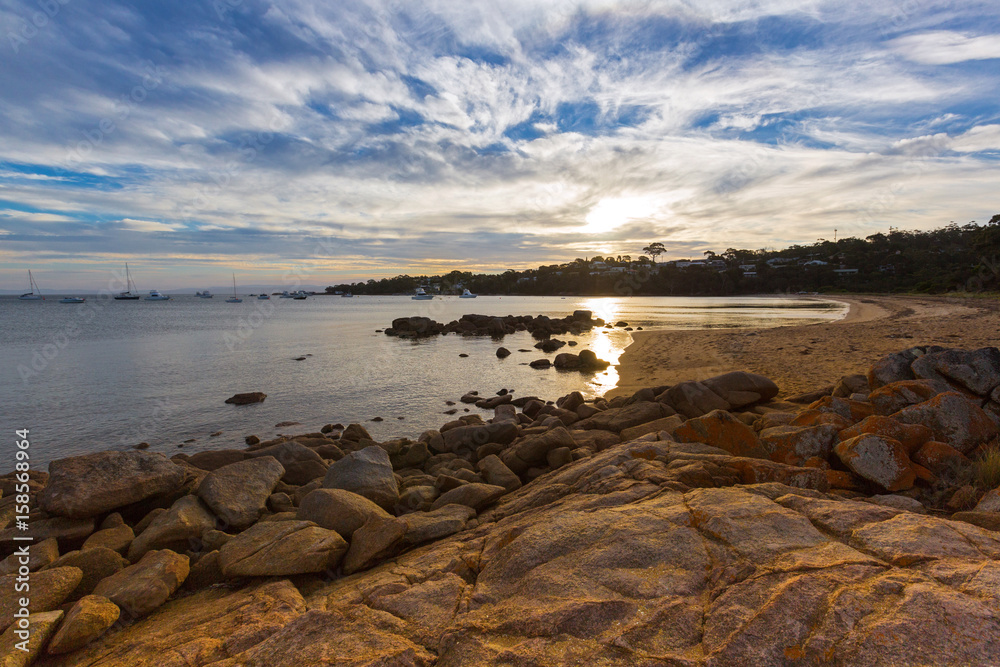 Obraz premium Evening sunset on Freycinet national park beach. Sunlight reflecting on Coles Bay, Tasmania, Australia.
