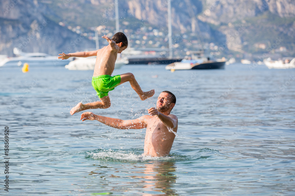 Child and his father, having fun in the sea, kid jumping in the water