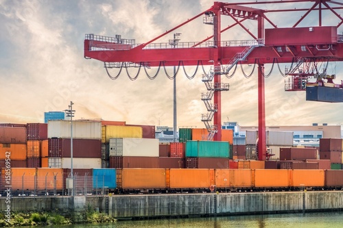 Transportation, shipping and logistics concept. Crane and many containers in harbour at sunset.