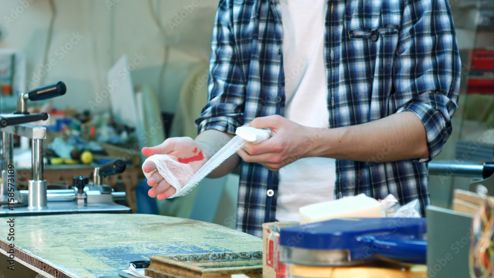Obraz premium Worker injured hand, laying a bandage on the wound