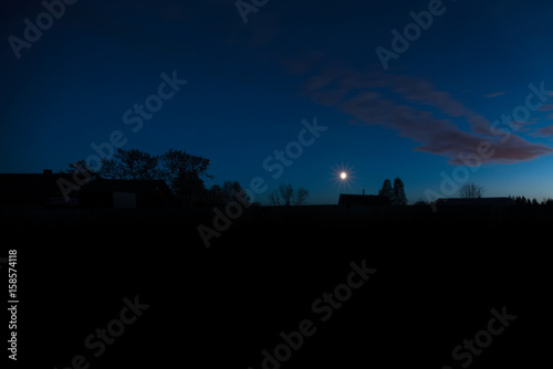 Night landscape with a star, clouds and silhouettes of houses and trees
