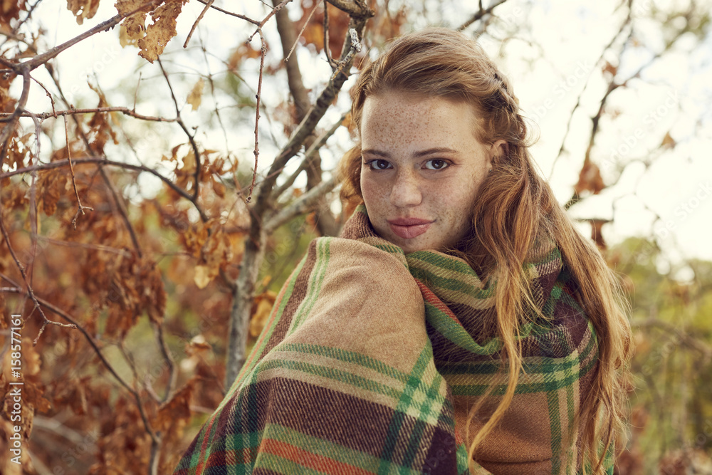 Portrait of redheaded young woman wrapped in blanket in autumnal nature Portrait of redheaded young woman wrapped in blanket in autumnal nature